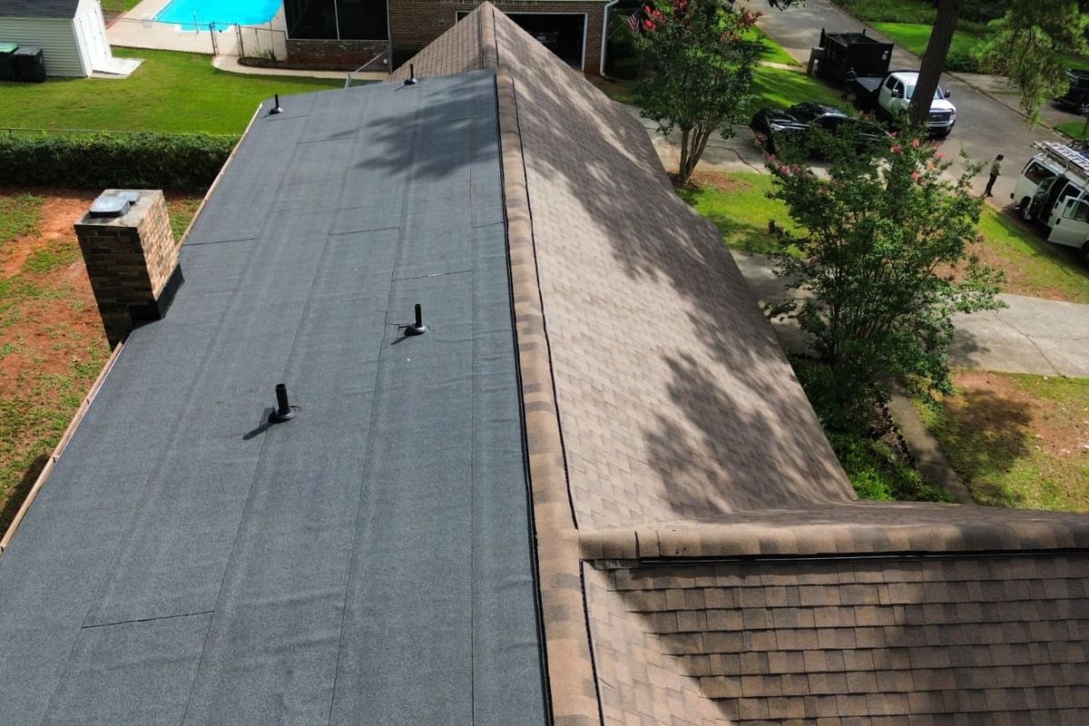 Finished gray shingle roof photographed from above, ridge vent running its length.