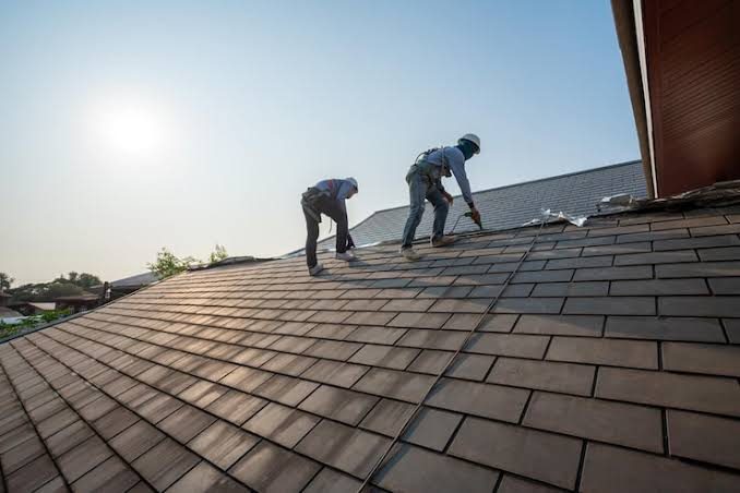 Two Response Roofing crew members working on a roof in the sun.