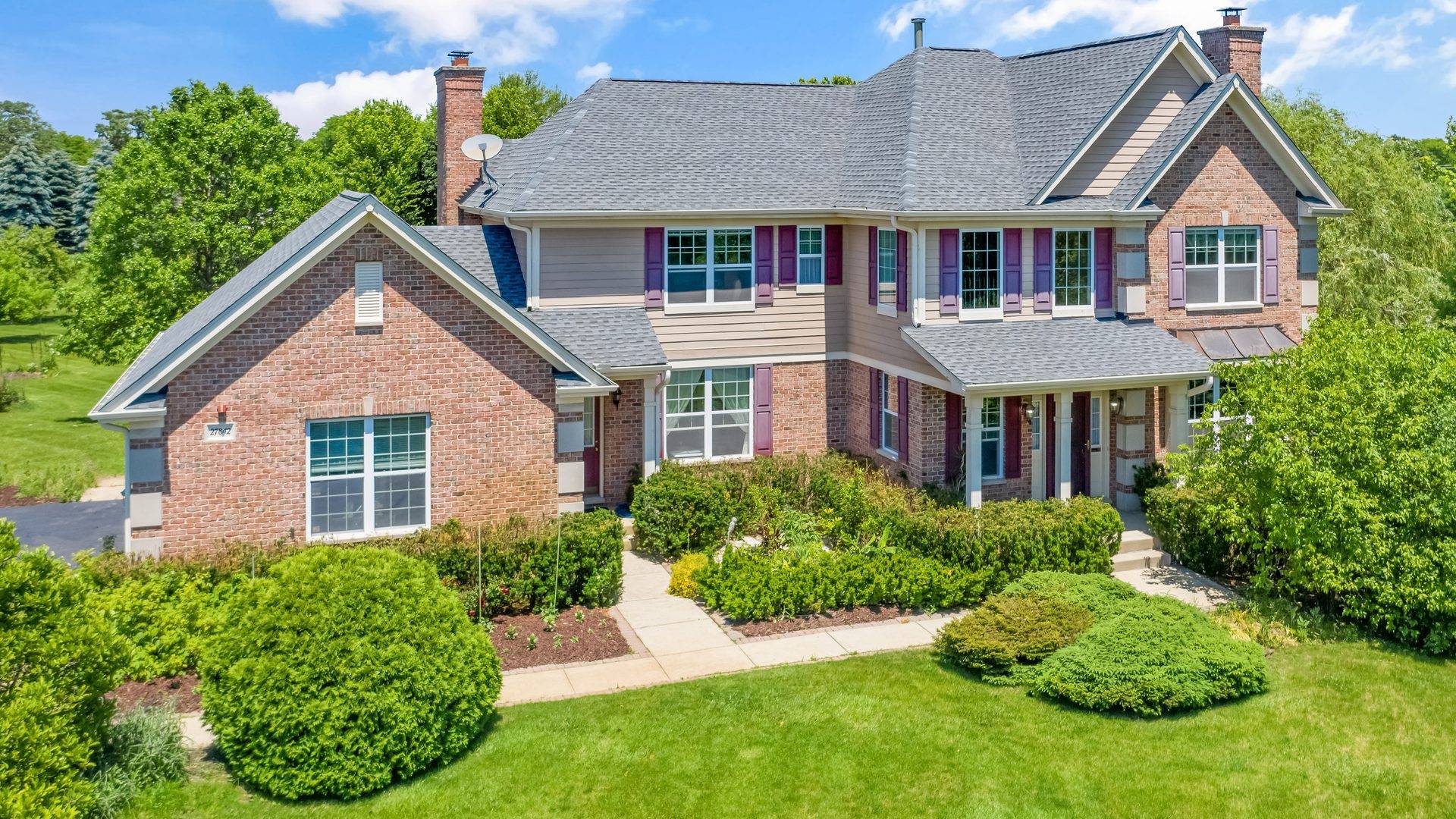 A traditional brick and siding home with a well-kept shingle roof.